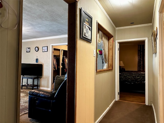 hall with crown molding, a textured ceiling, and dark colored carpet