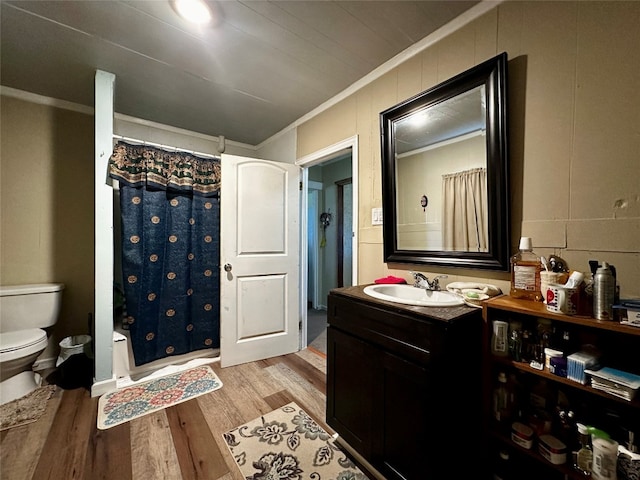 bathroom with toilet, vanity with extensive cabinet space, ornamental molding, and hardwood / wood-style flooring