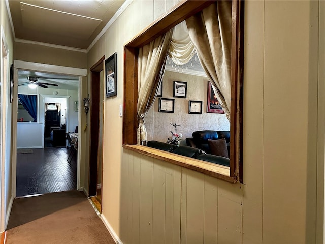 hall with crown molding and dark colored carpet