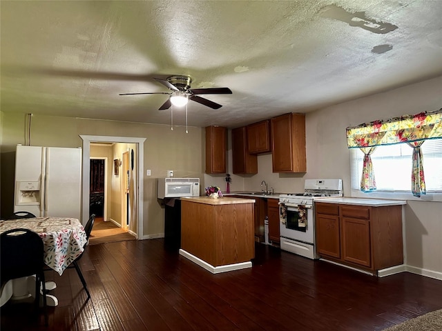 kitchen featuring ceiling fan, white appliances, dark hardwood / wood-style floors, and a kitchen island