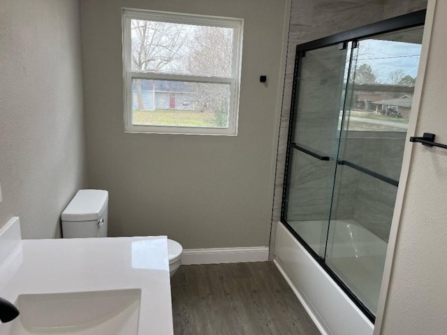 full bathroom with vanity, hardwood / wood-style flooring, toilet, and bath / shower combo with glass door