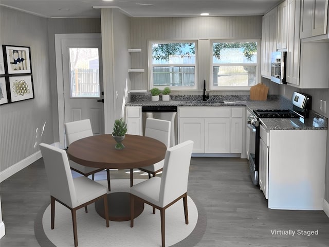 kitchen featuring a healthy amount of sunlight, dark stone countertops, stainless steel appliances, and dark hardwood / wood-style floors