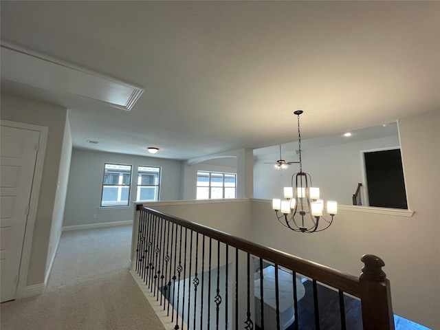 hallway featuring light carpet and an inviting chandelier