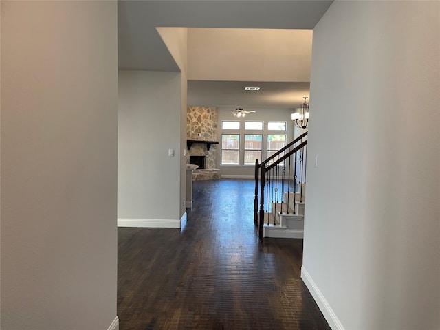 corridor with dark hardwood / wood-style floors and an inviting chandelier