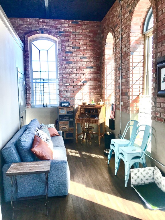 living room featuring dark hardwood / wood-style flooring and brick wall