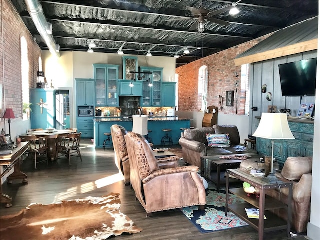 interior space with ceiling fan, brick wall, and dark wood-type flooring