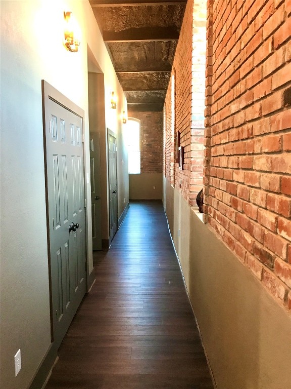 hall featuring brick wall and dark wood-type flooring