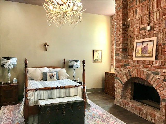 bedroom featuring a fireplace, brick wall, dark hardwood / wood-style floors, and a chandelier