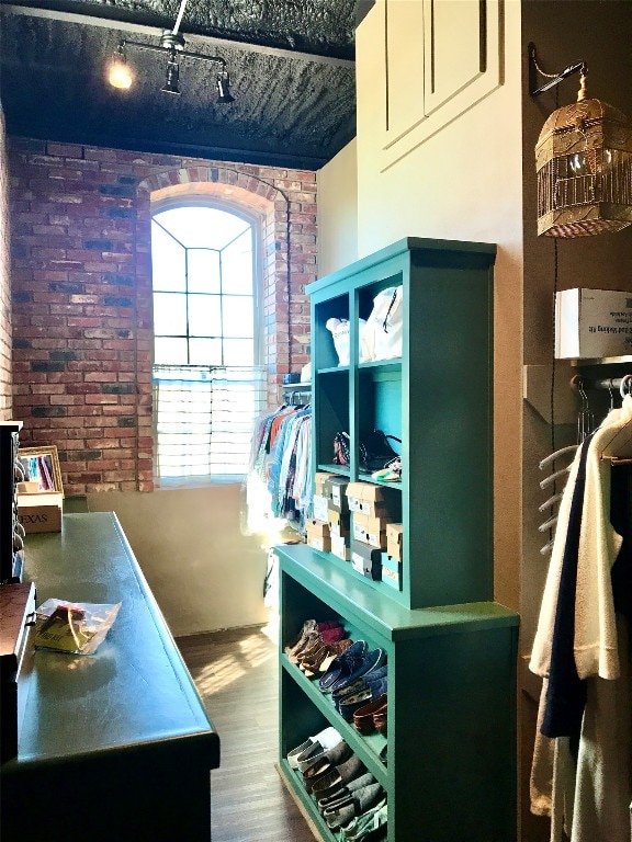 kitchen with brick wall and dark wood-type flooring