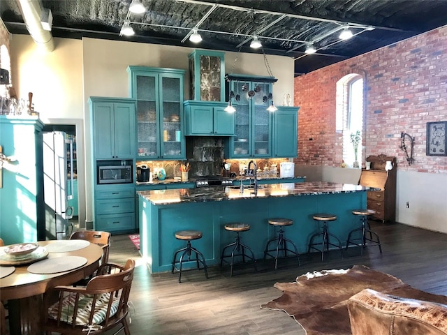 kitchen featuring brick wall, a kitchen bar, stainless steel microwave, and dark hardwood / wood-style flooring