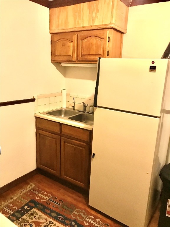 kitchen featuring dark hardwood / wood-style floors, sink, and white fridge