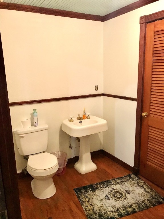 bathroom featuring toilet, ornamental molding, and wood-type flooring