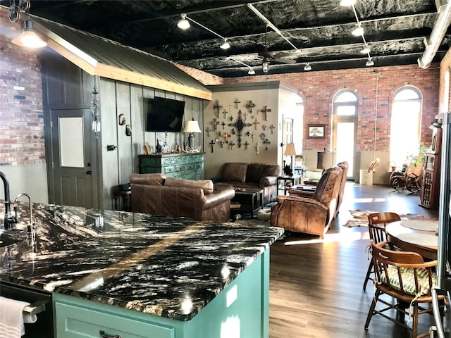 kitchen featuring brick wall, green cabinets, and hardwood / wood-style flooring