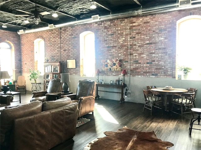 living room featuring dark hardwood / wood-style flooring, brick wall, and plenty of natural light