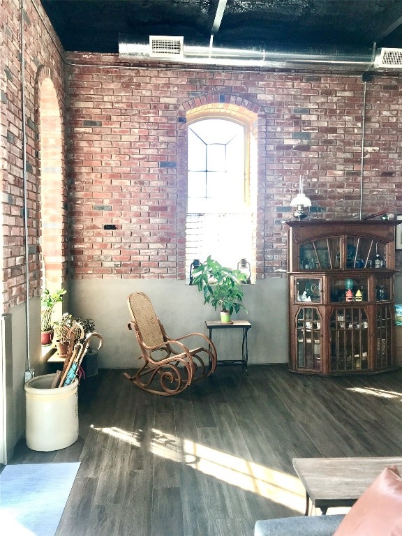 unfurnished room featuring brick wall and dark wood-type flooring