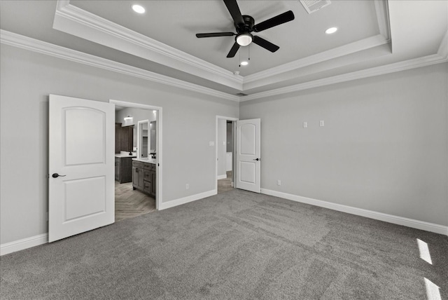 unfurnished bedroom featuring a raised ceiling, ceiling fan, crown molding, and ensuite bathroom