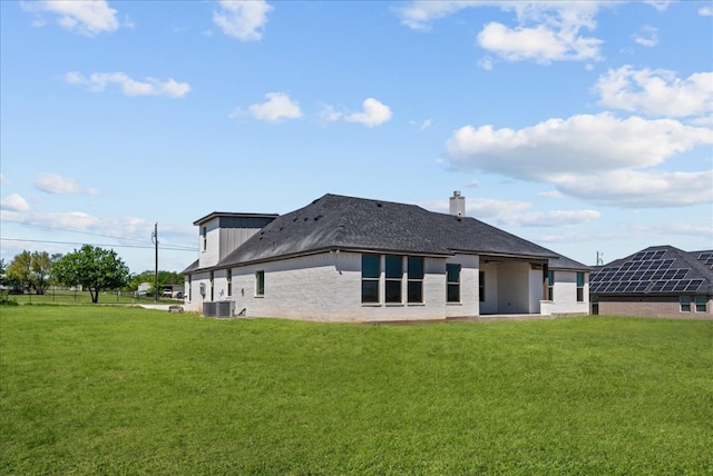 rear view of house with central AC and a lawn