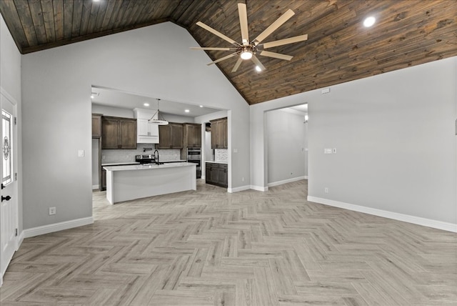 kitchen with tasteful backsplash, a kitchen island with sink, high vaulted ceiling, and light parquet flooring