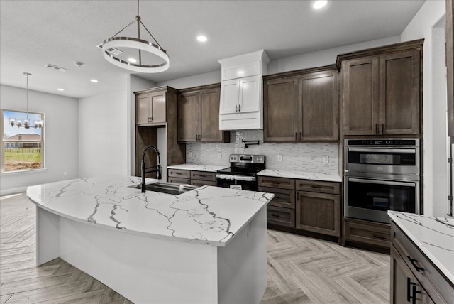 kitchen with pendant lighting, light parquet floors, appliances with stainless steel finishes, sink, and light stone counters