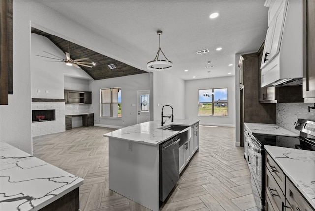 kitchen featuring an island with sink, light parquet floors, pendant lighting, and range with electric stovetop