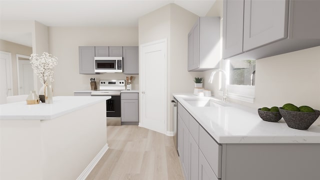 kitchen featuring gray cabinetry, sink, light hardwood / wood-style floors, and stainless steel appliances