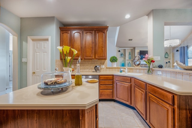 kitchen with sink, light tile patterned floors, kitchen peninsula, and a kitchen island