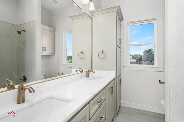 bathroom featuring toilet, dual vanity, and crown molding