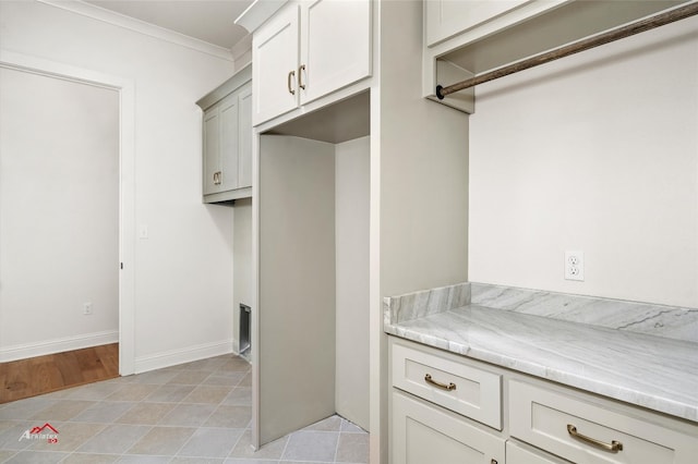 laundry area featuring ornamental molding and light tile floors