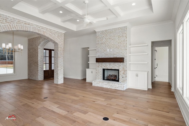 unfurnished living room featuring coffered ceiling, a brick fireplace, light hardwood / wood-style flooring, beam ceiling, and french doors