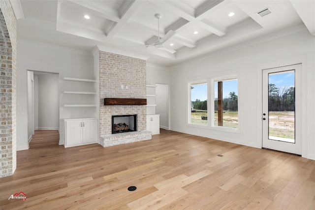 unfurnished living room featuring coffered ceiling, ceiling fan, a brick fireplace, light hardwood / wood-style flooring, and beam ceiling