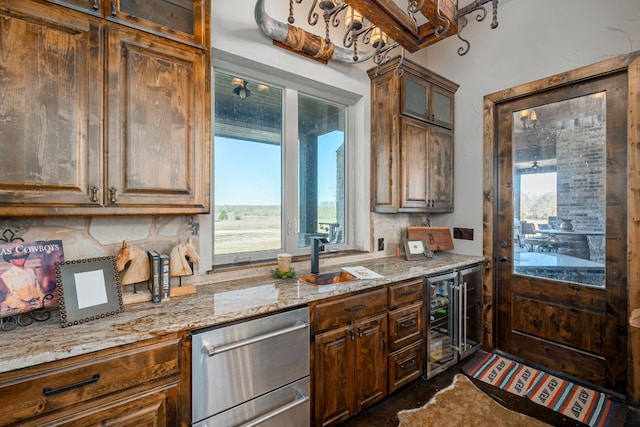 kitchen with light stone countertops, beverage cooler, dishwasher, and sink