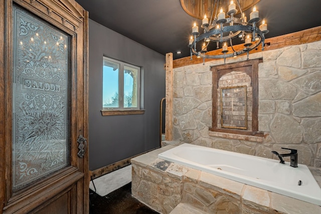 bathroom featuring a notable chandelier and tiled tub