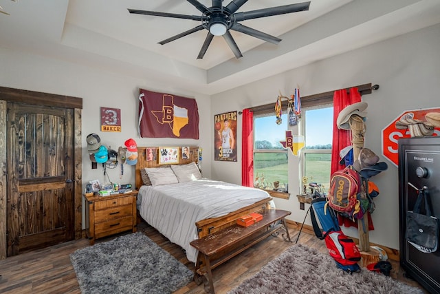 bedroom with a tray ceiling, ceiling fan, and dark hardwood / wood-style floors