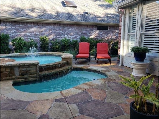 view of swimming pool with pool water feature and an in ground hot tub