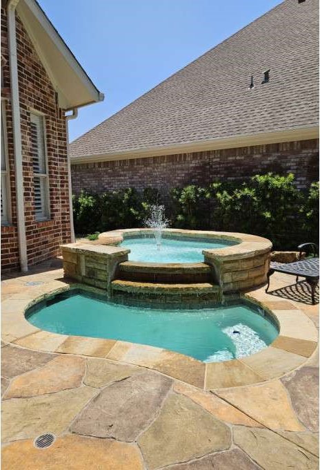 view of swimming pool with a patio, pool water feature, and an in ground hot tub