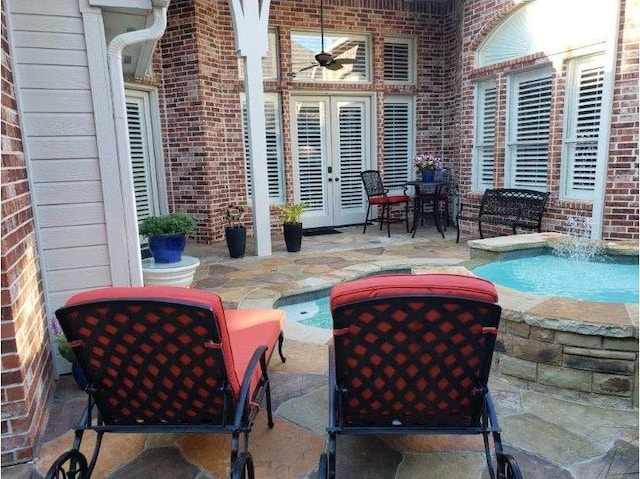 view of patio / terrace featuring ceiling fan, french doors, a jacuzzi, and pool water feature