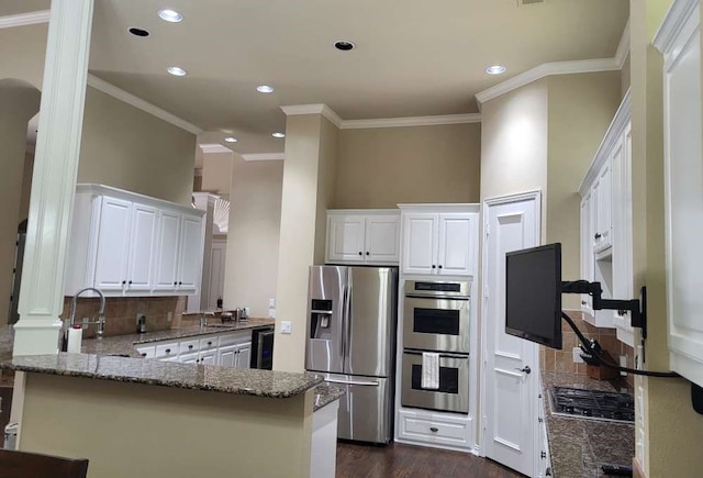 kitchen featuring kitchen peninsula, tasteful backsplash, dark wood-type flooring, white cabinets, and appliances with stainless steel finishes