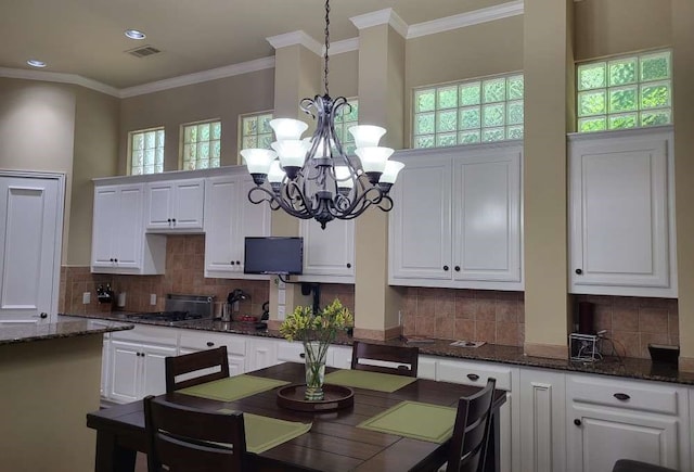 dining room featuring a towering ceiling, a chandelier, and ornamental molding