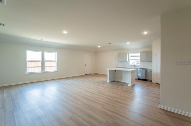 unfurnished living room with light hardwood / wood-style flooring, sink, and plenty of natural light