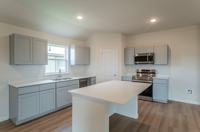 kitchen featuring appliances with stainless steel finishes, gray cabinetry, sink, light hardwood / wood-style floors, and a center island