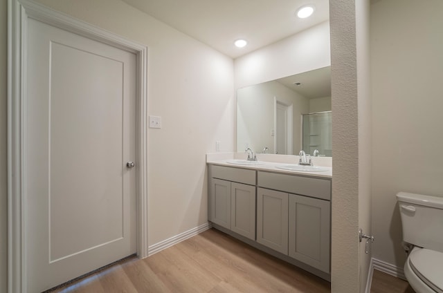 bathroom featuring wood-type flooring, double sink vanity, and toilet