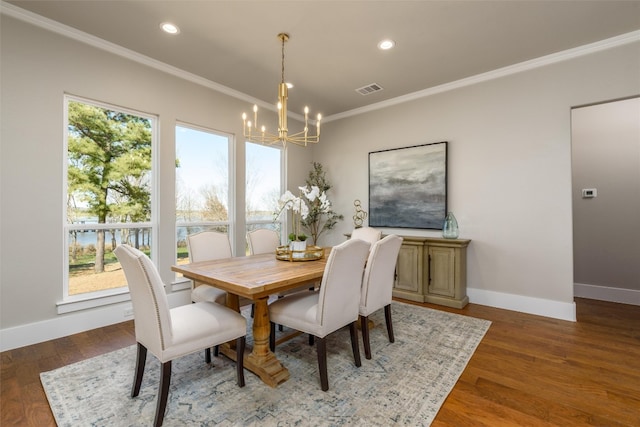 dining room featuring wood-type flooring, ornamental molding, and an inviting chandelier