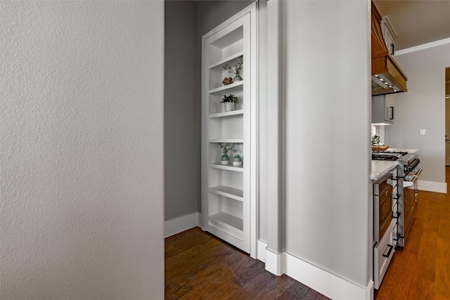 hallway with dark hardwood / wood-style floors and built in shelves