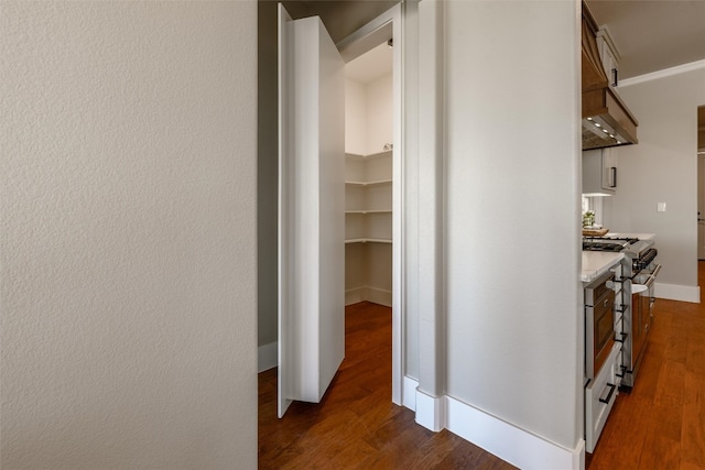 corridor with ornamental molding and dark hardwood / wood-style flooring