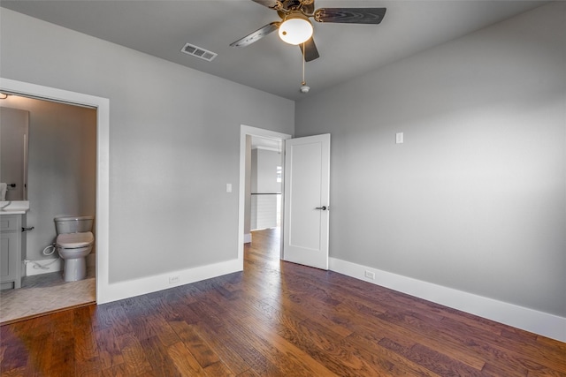 unfurnished bedroom featuring connected bathroom, dark hardwood / wood-style floors, and ceiling fan