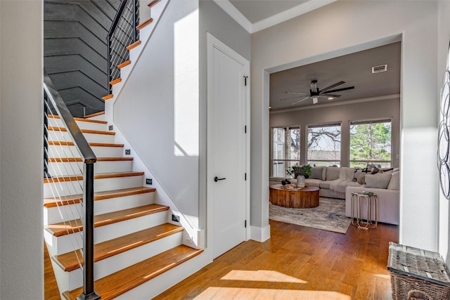 stairs featuring ceiling fan, crown molding, and hardwood / wood-style flooring