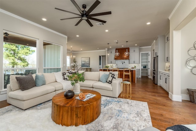 living room featuring ceiling fan with notable chandelier, light hardwood / wood-style floors, and crown molding