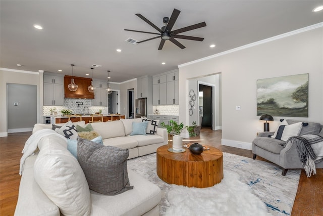 living room with ornamental molding, ceiling fan, and light hardwood / wood-style flooring