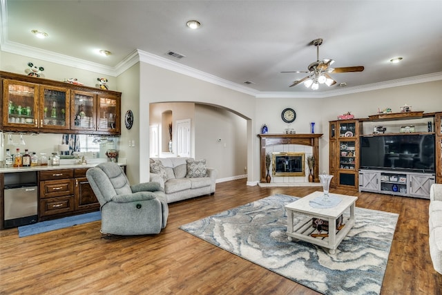 living room with ornamental molding, wood-type flooring, and ceiling fan