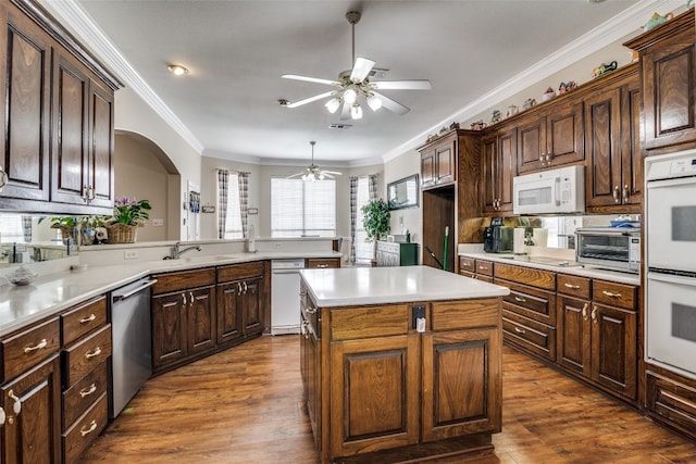 kitchen featuring dark hardwood / wood-style floors, a center island, ceiling fan, white appliances, and ornamental molding